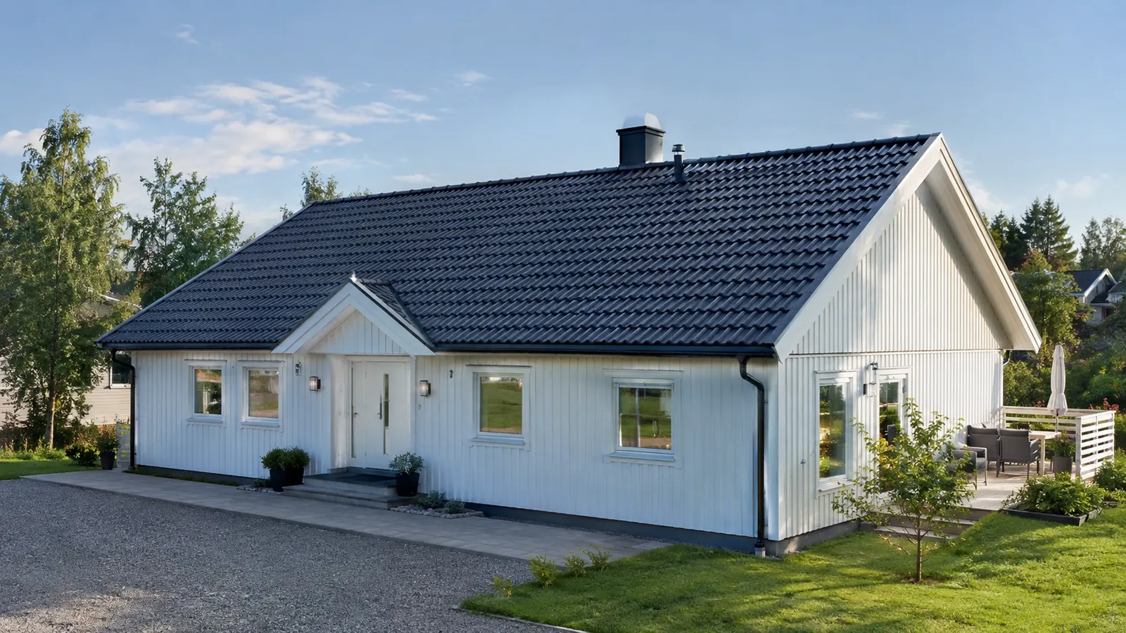 Vit villa med ett nylagt mörkt tak av takpannor, en klar sommardag.
